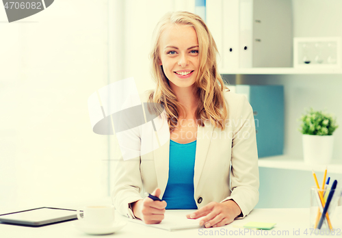Image of businesswoman writing to notebook at office