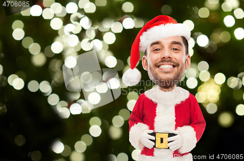 Image of smiling man in santa costume over christmas tree
