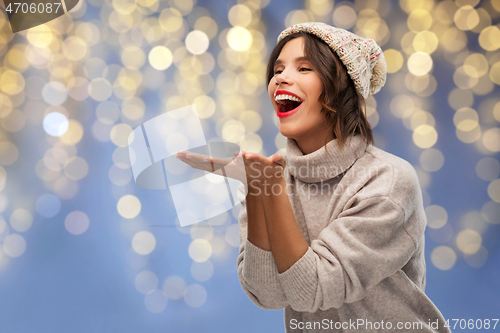 Image of woman in winter hat sending air kiss on christmas