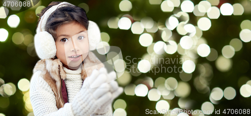 Image of happy little girl in earmuffs over winter forest