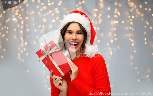 Image of happy woman in santa hat with red christmas gift