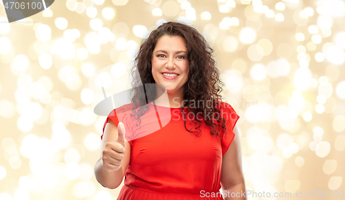 Image of happy woman showing thumbs up over lights