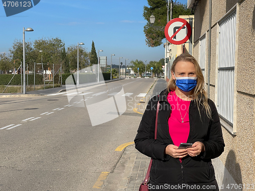 Image of Alone in empty street. Urban portrait of a woman in mask