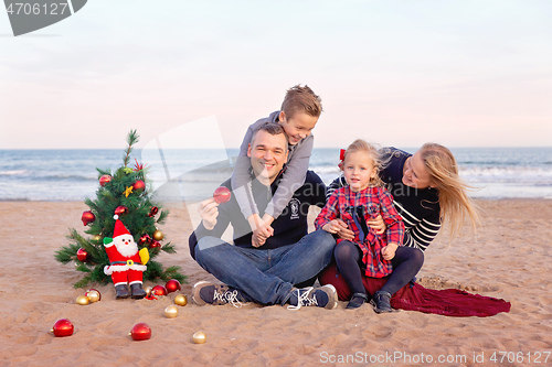 Image of Christmas portrait of happy family on the beach