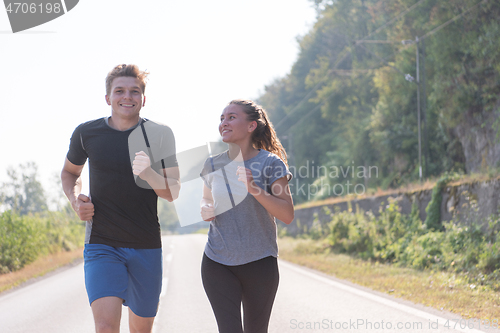 Image of young couple jogging along a country road