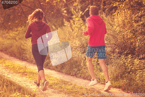 Image of young couple jogging along a country road