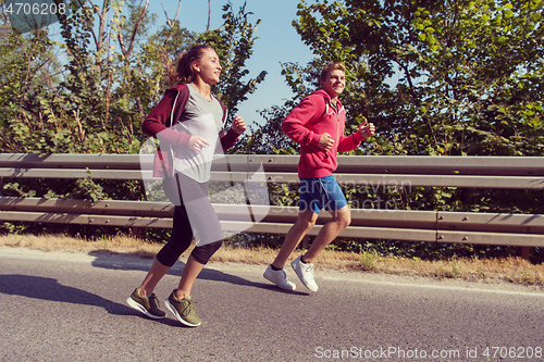 Image of young couple jogging along a country road