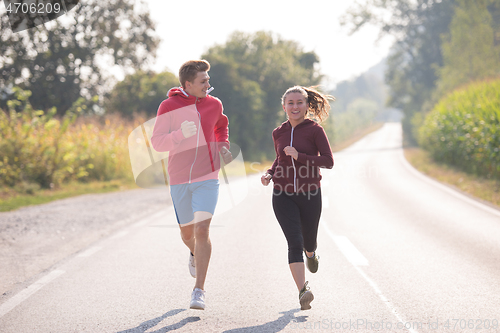 Image of young couple jogging along a country road