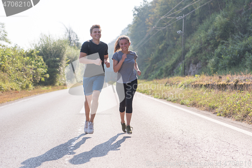 Image of young couple jogging along a country road