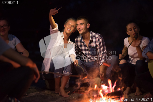 Image of young friends relaxing around campfire