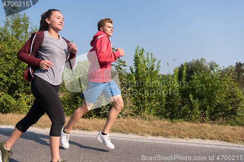 Image of young couple jogging along a country road