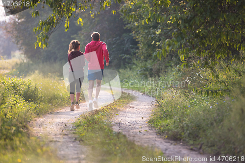 Image of young couple jogging along a country road