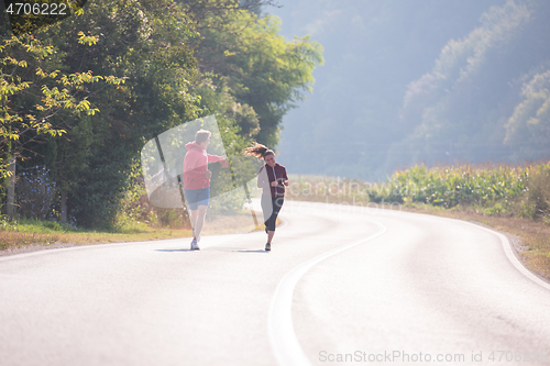 Image of young couple jogging along a country road