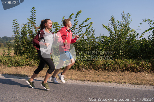 Image of young couple jogging along a country road