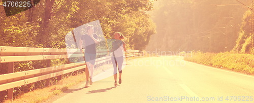 Image of young couple jogging along a country road