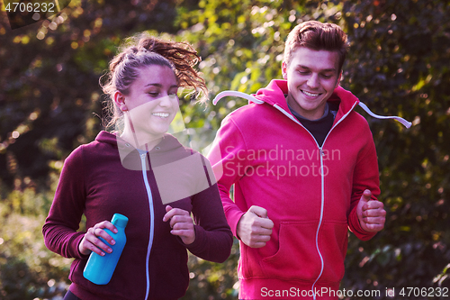 Image of young couple jogging along a country road