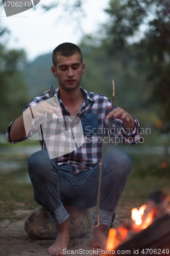 Image of young friends relaxing around campfire