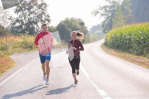 Image of young couple jogging along a country road