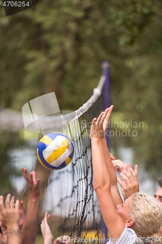Image of group of young friends playing Beach volleyball