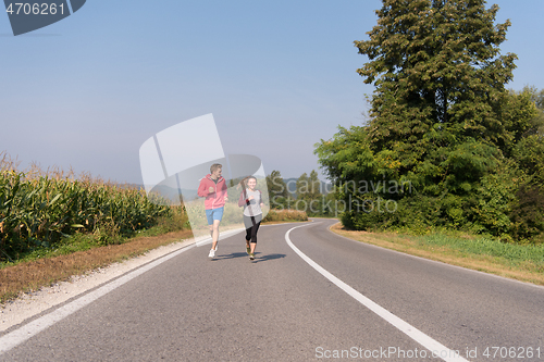 Image of young couple jogging along a country road