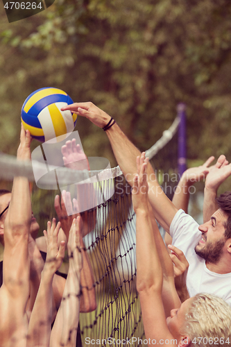 Image of group of young friends playing Beach volleyball