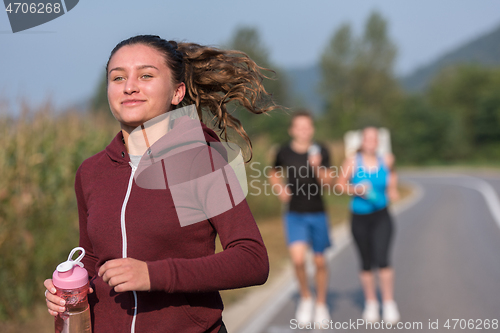 Image of young people jogging on country road