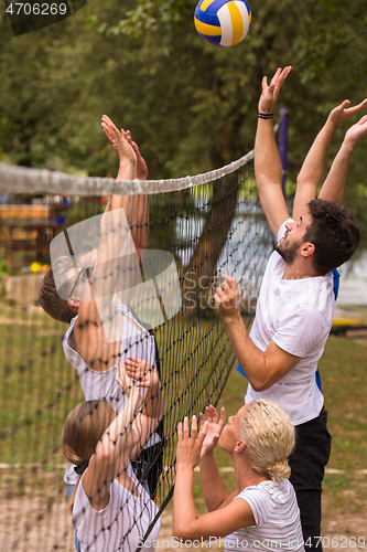 Image of group of young friends playing Beach volleyball