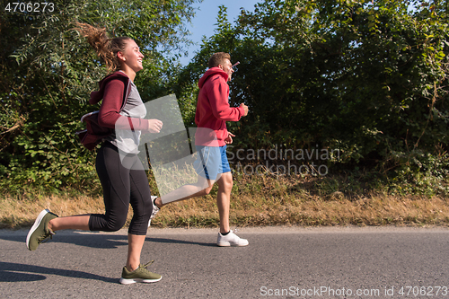 Image of young couple jogging along a country road