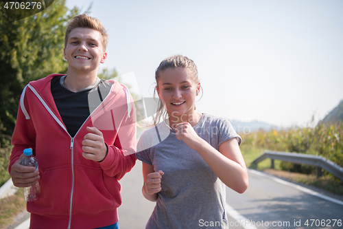 Image of young couple jogging along a country road