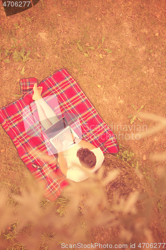 Image of top view of man using a laptop computer under the tree