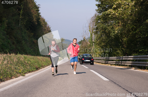 Image of young couple jogging along a country road