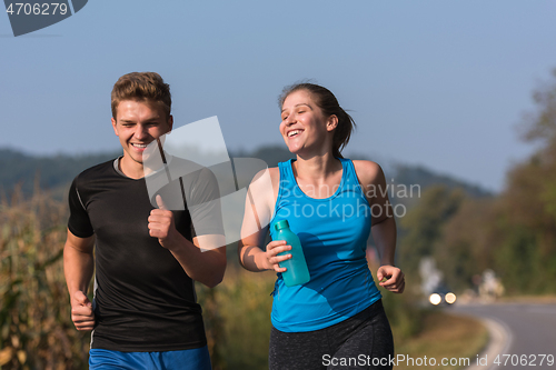 Image of young couple jogging along a country road