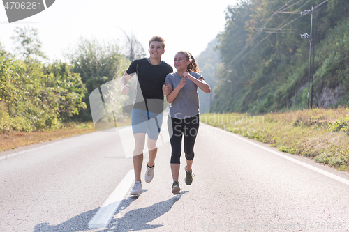 Image of young couple jogging along a country road