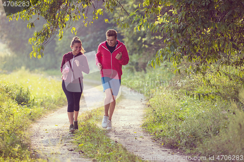 Image of young couple jogging along a country road