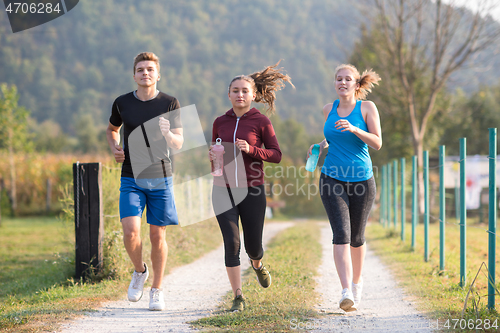 Image of young people jogging on country road