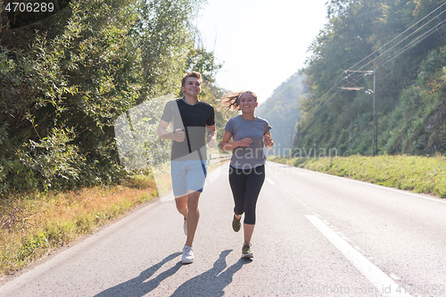 Image of young couple jogging along a country road