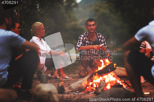 Image of young friends relaxing around campfire