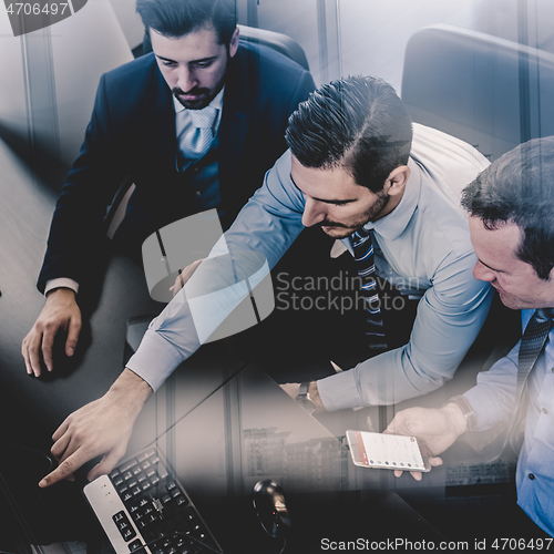 Image of Businessmen trading stocks. Stock traders looking at graphs, indexes and numbers on multiple computer screens. Colleagues in discussion in traders office. Business success concept