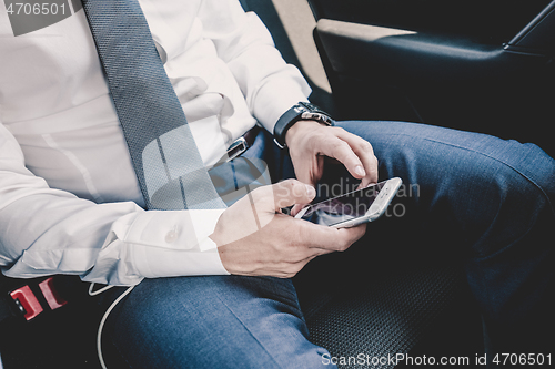 Image of Close up of businessman using mobile smart phone in a car.