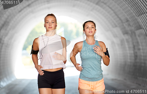Image of young women with earphones and smartphones running