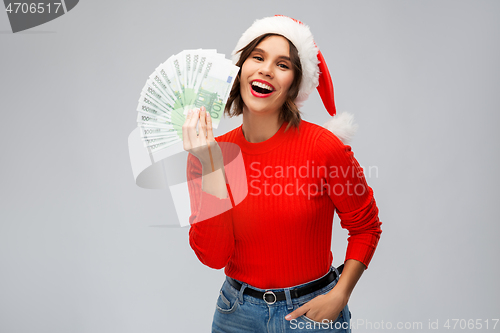 Image of happy woman in santa hat with money on christmas