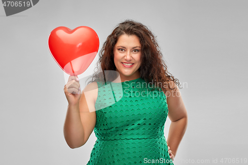 Image of happy woman holding red heart shaped balloon