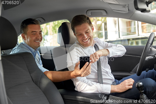 Image of male passenger showing smartphone to car driver