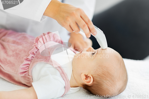 Image of doctor with thermometer measures baby temperature