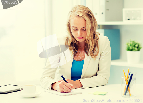 Image of businesswoman writing to notebook at office