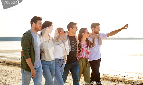 Image of happy friends walking along summer beach