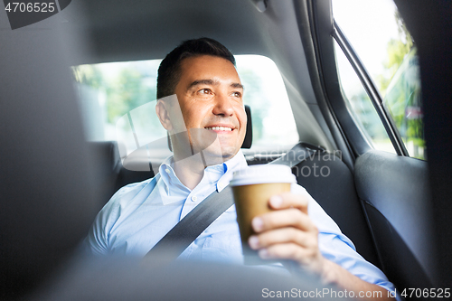 Image of businessman with takeaway coffee on car back seat