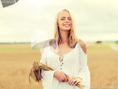 Image of happy young woman with spikelets on cereal field