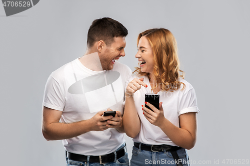 Image of happy couple in white t-shirts with smartphones
