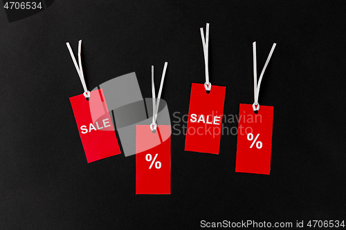 Image of red tags with discount signs on black background